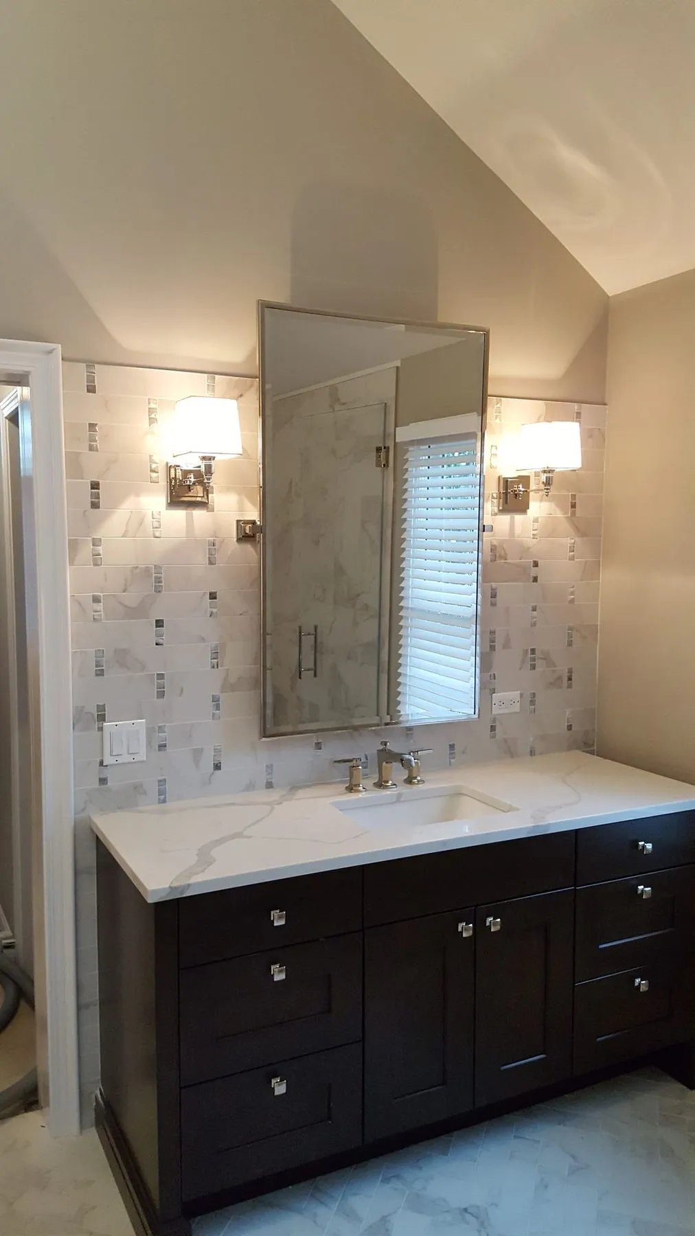 Vanity with marble backsplash and wall sconces