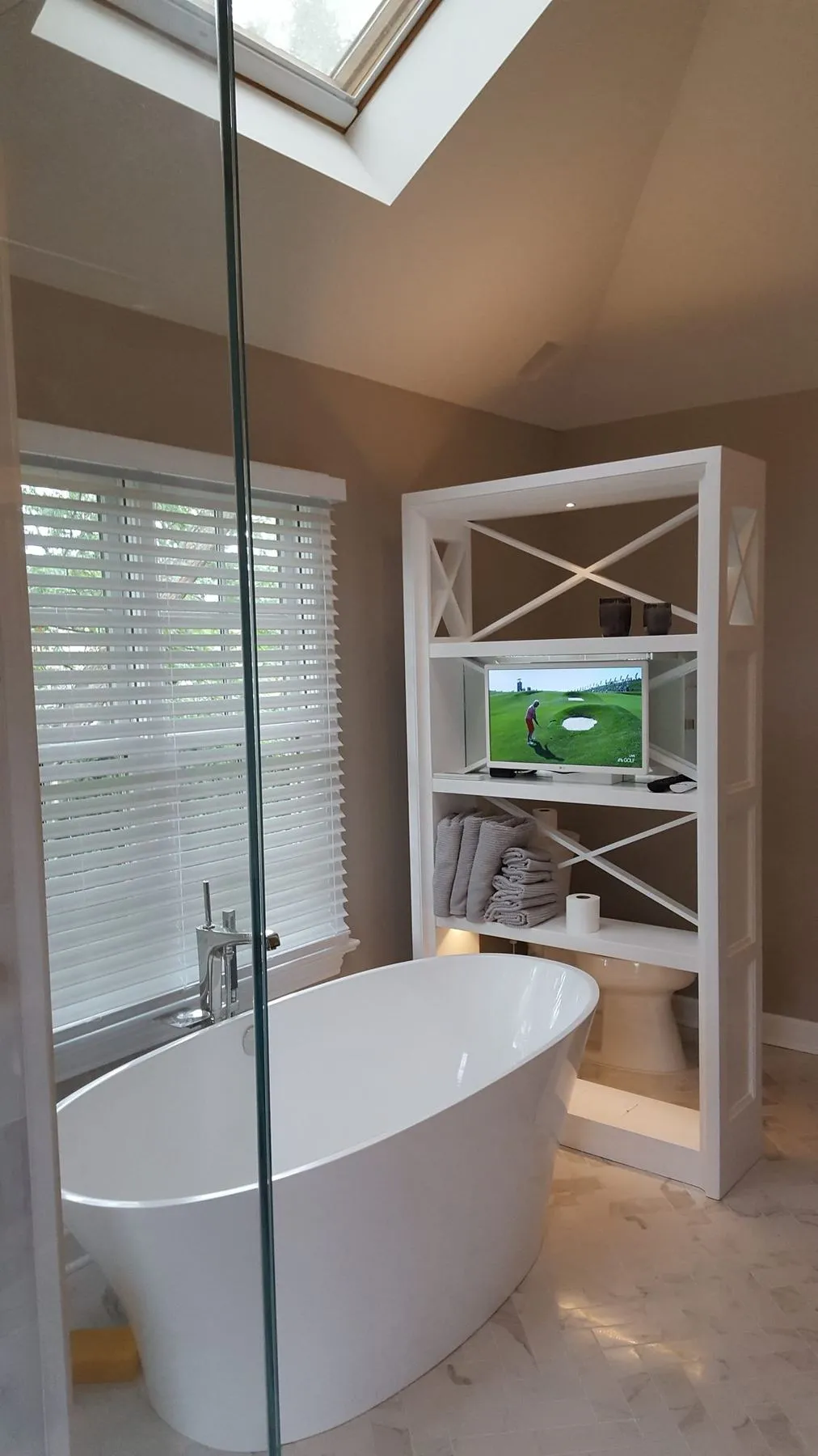 Freestanding tub under a window beside shelving