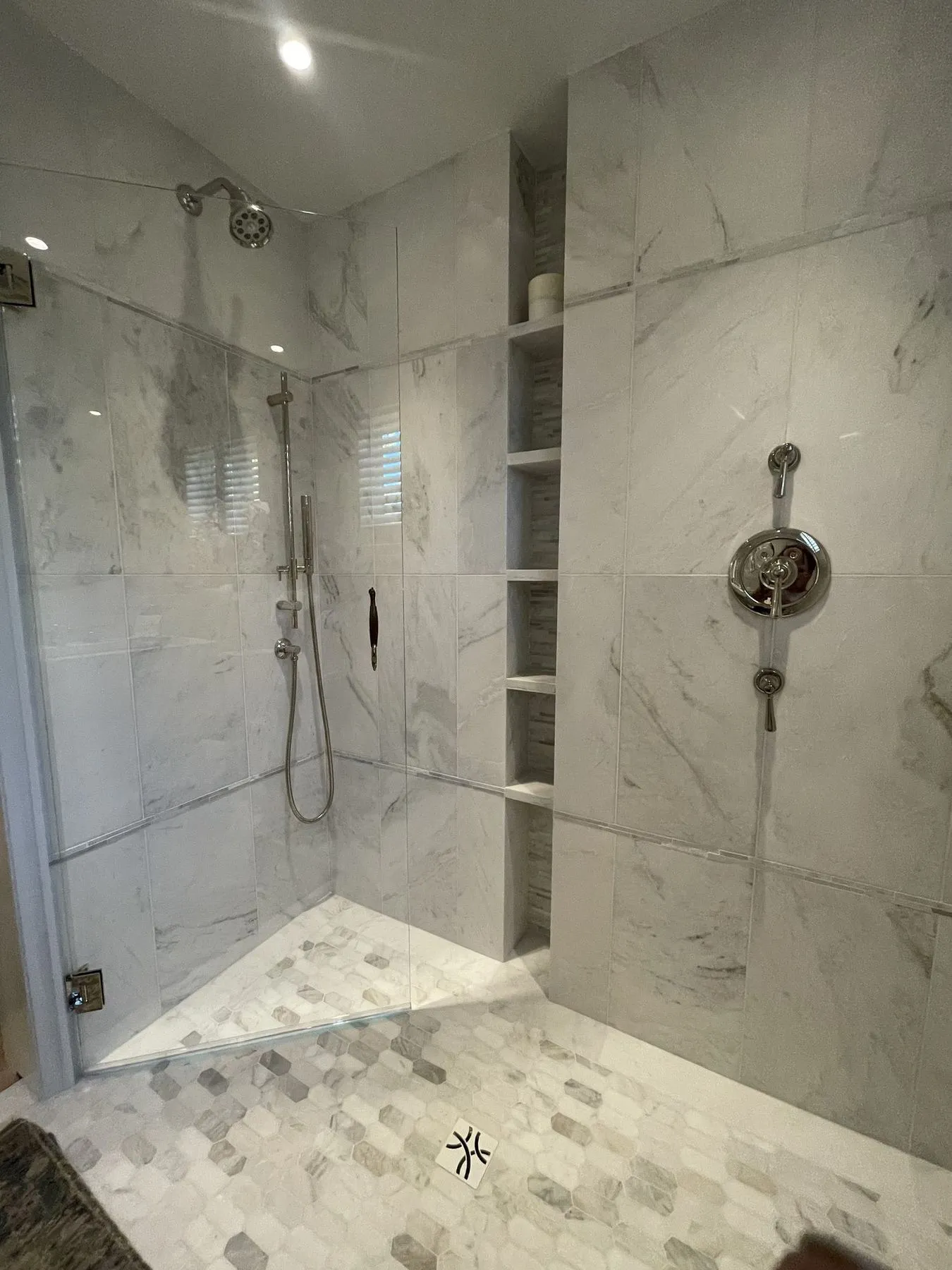 Walk-in shower with marble-look tile and a tall niche