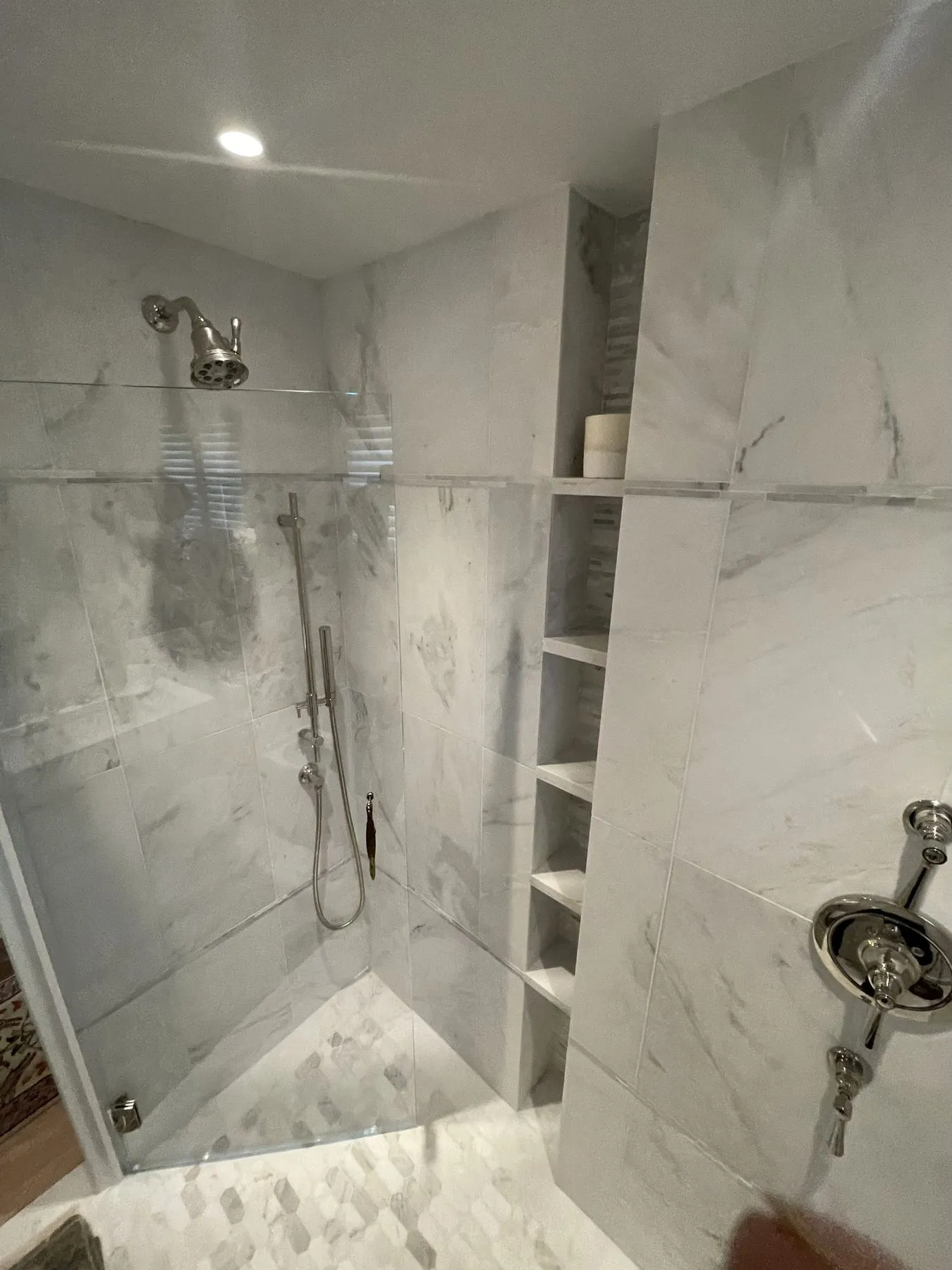 Shower valve and handheld shower on marble tile