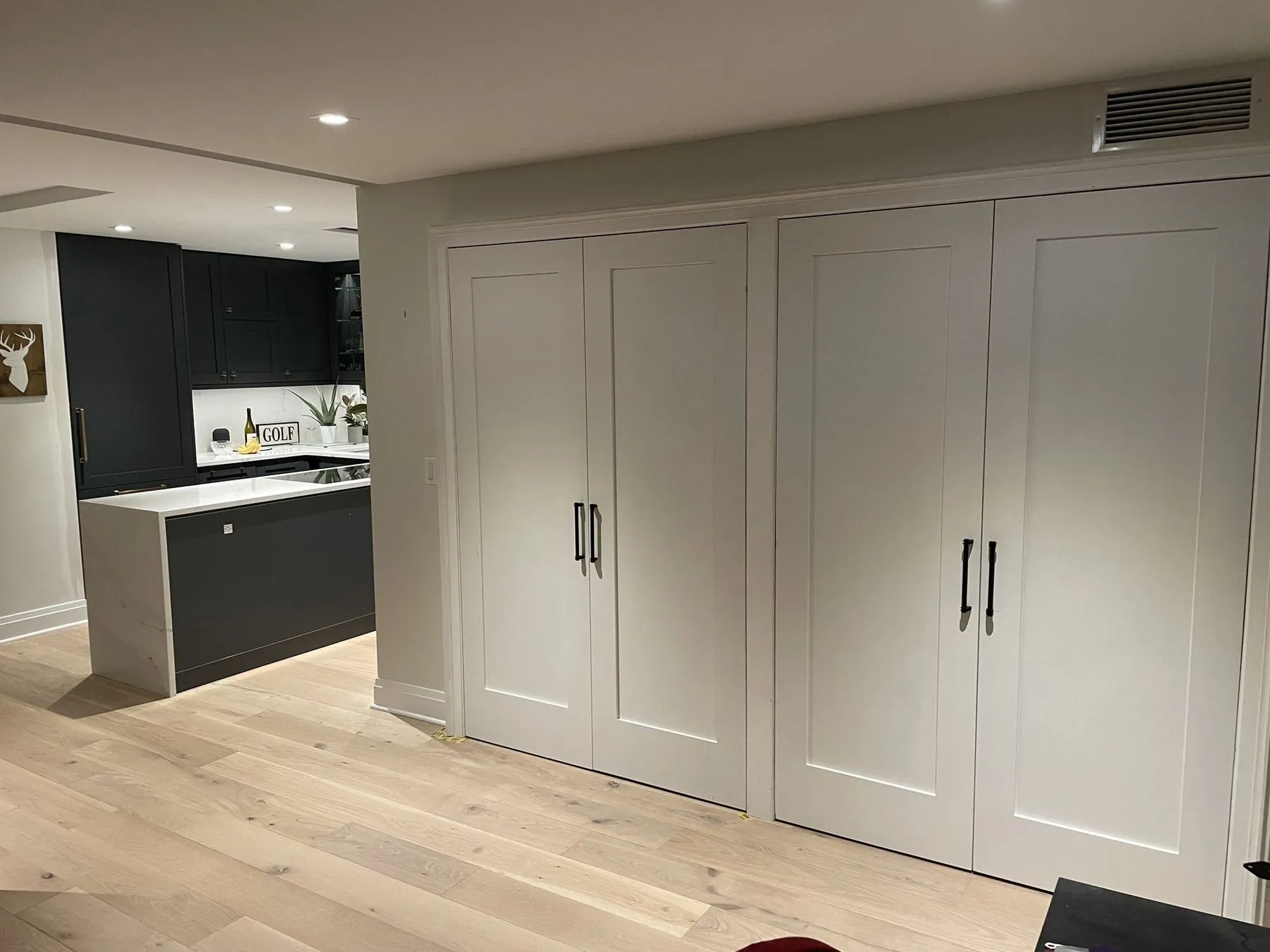Wall of built-in closets with the kitchen beyond