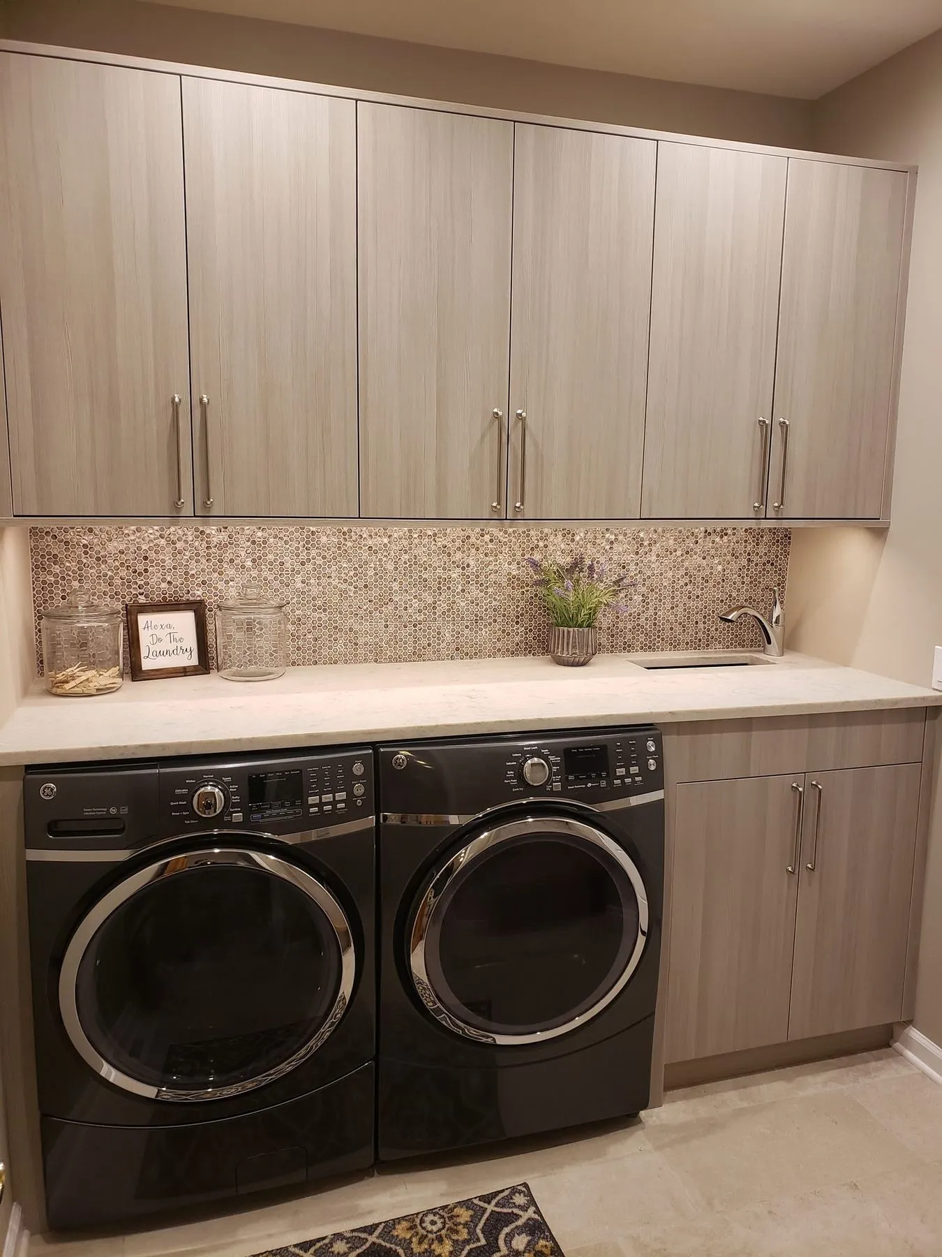 Laundry room with wood-grain cabinets and a mosaic backsplash