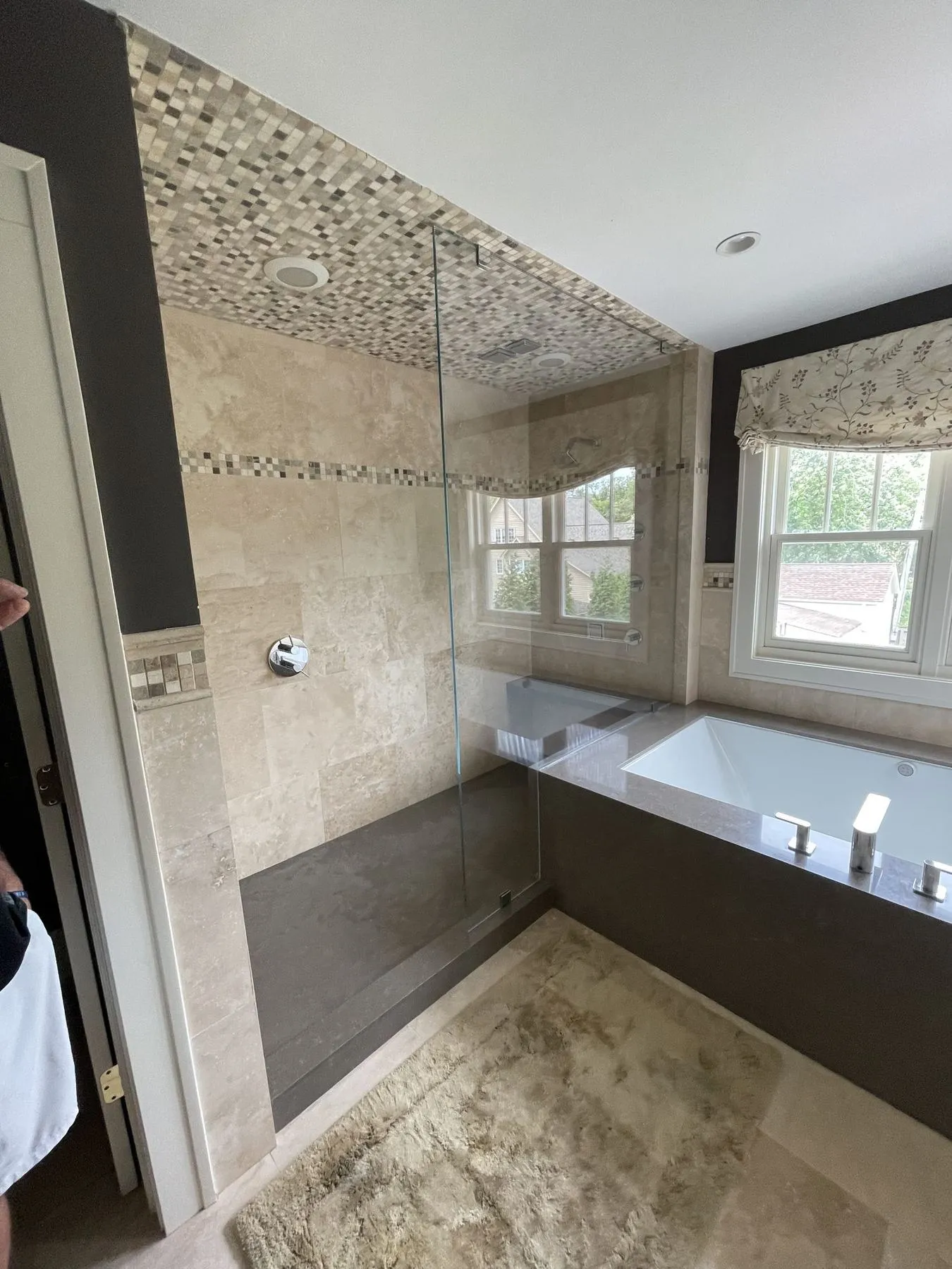 Glass shower and soaking tub under a window