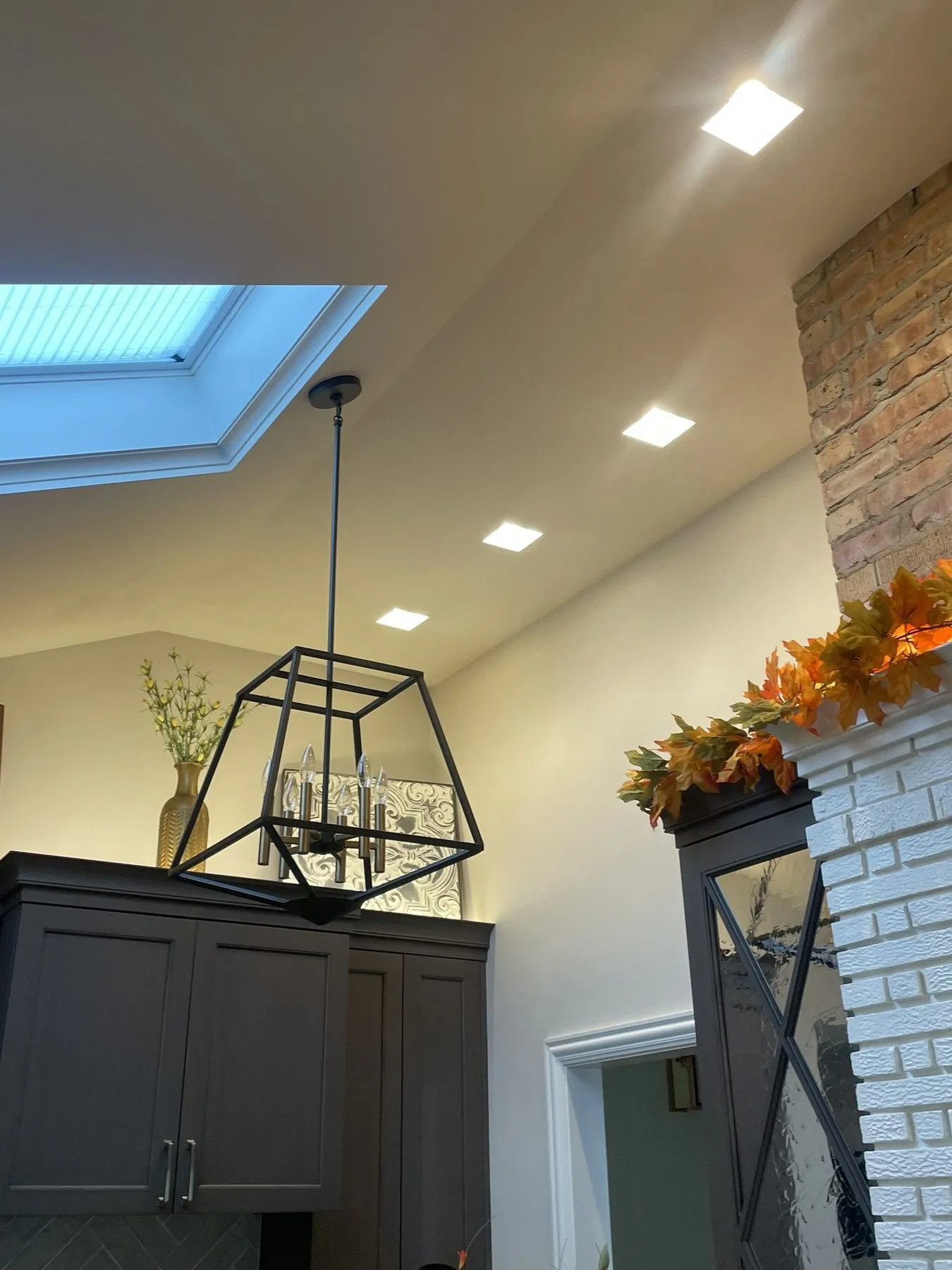 Lantern pendant under a skylight with dark cabinets below