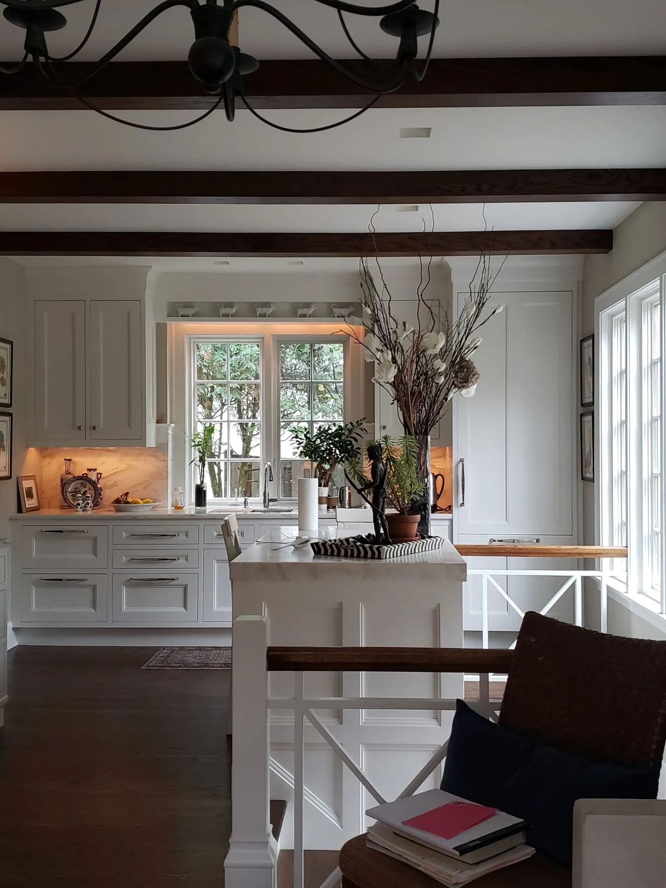 White kitchen under dark ceiling beams seen from the family room