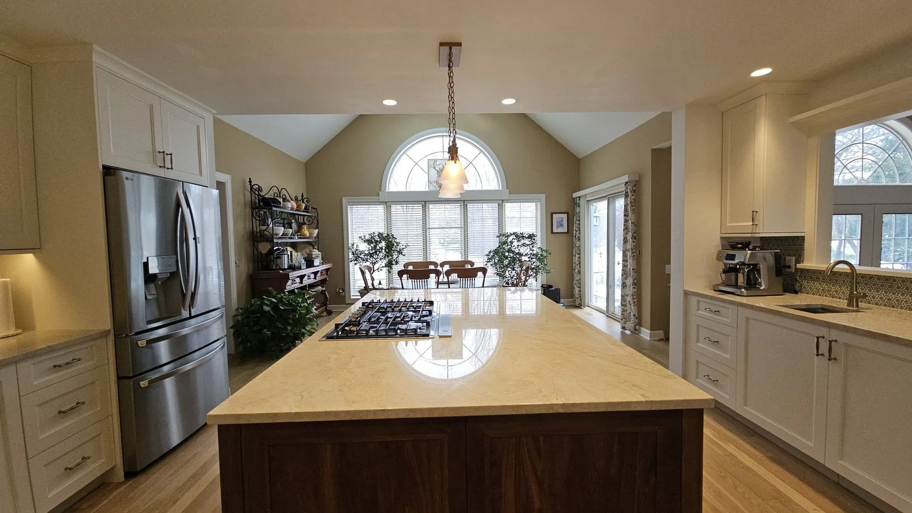 White kitchen with a walnut island and an arched window