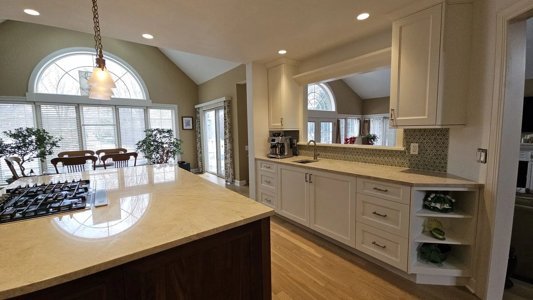 Island with a gas cooktop facing an arched window and eating area